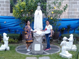 Two women standing by the statue of Our Lady of Fatima