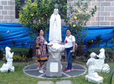 Two women standing by the statue of Our Lady of Fatima
